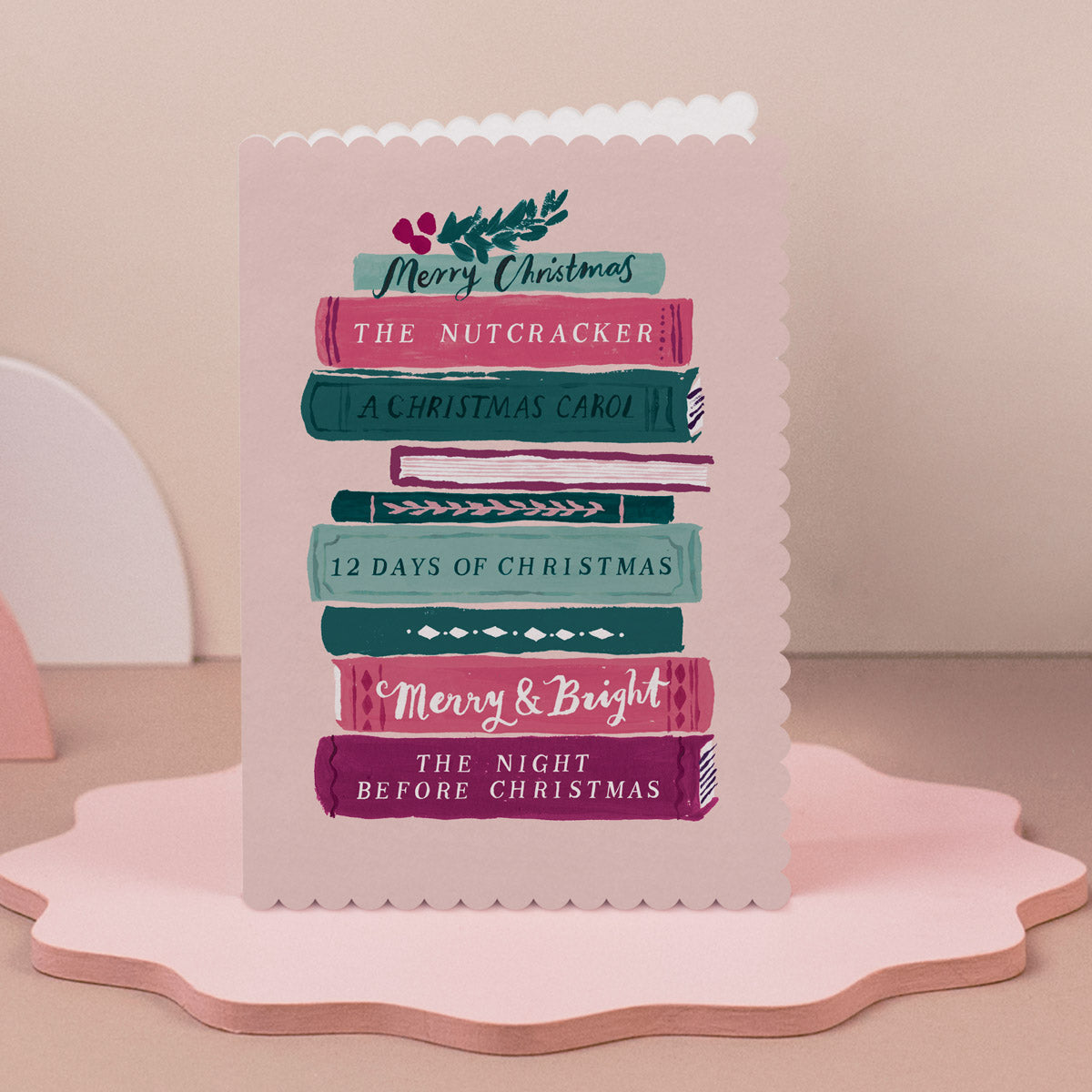 Bookish Christmas card, the Christmas book stack design appeals to those that love BookTok, it's on a pink scalloped edge stand.
