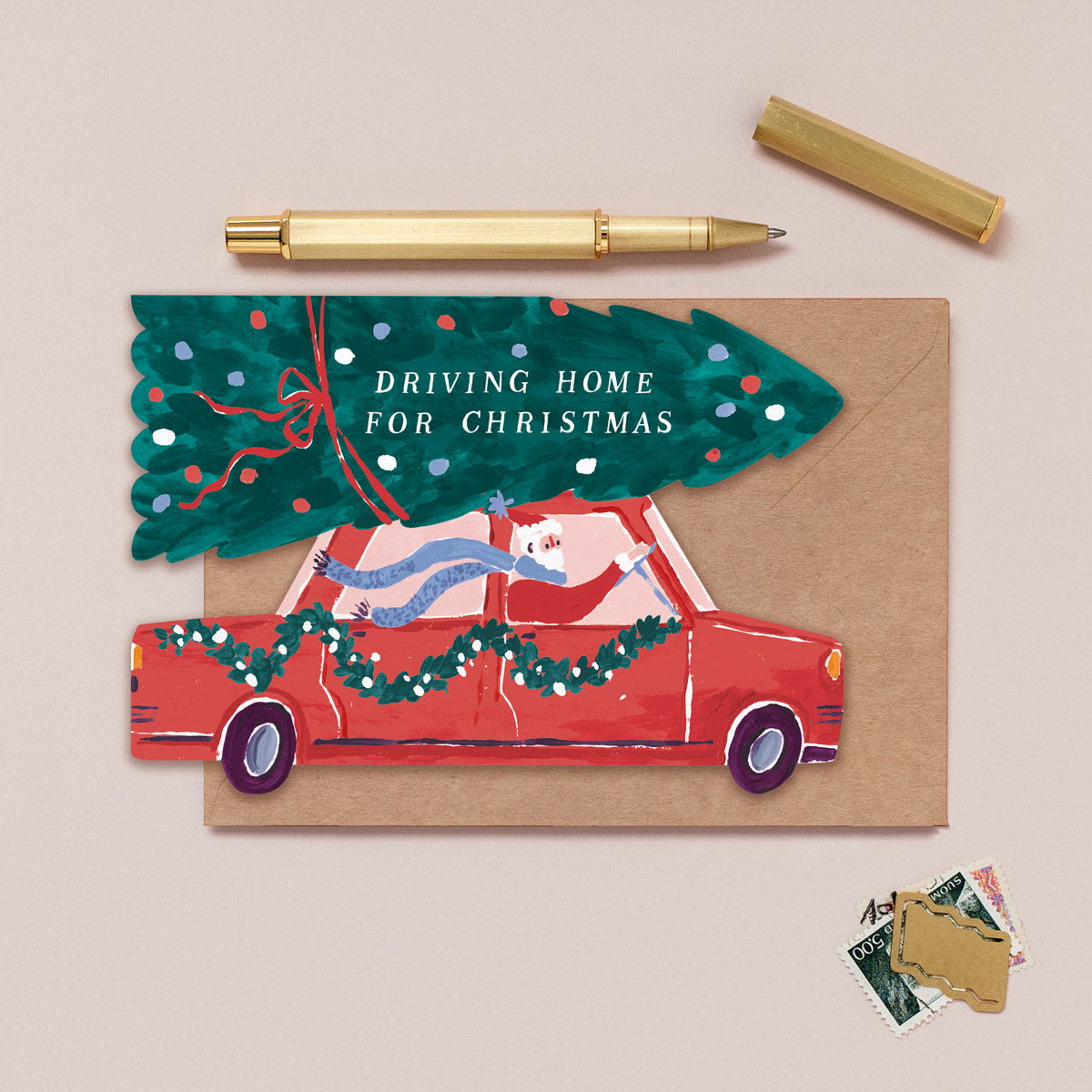 Christmas card with a red car and tree, featuring the text 'Driving Home for Christmas', on a beige background.