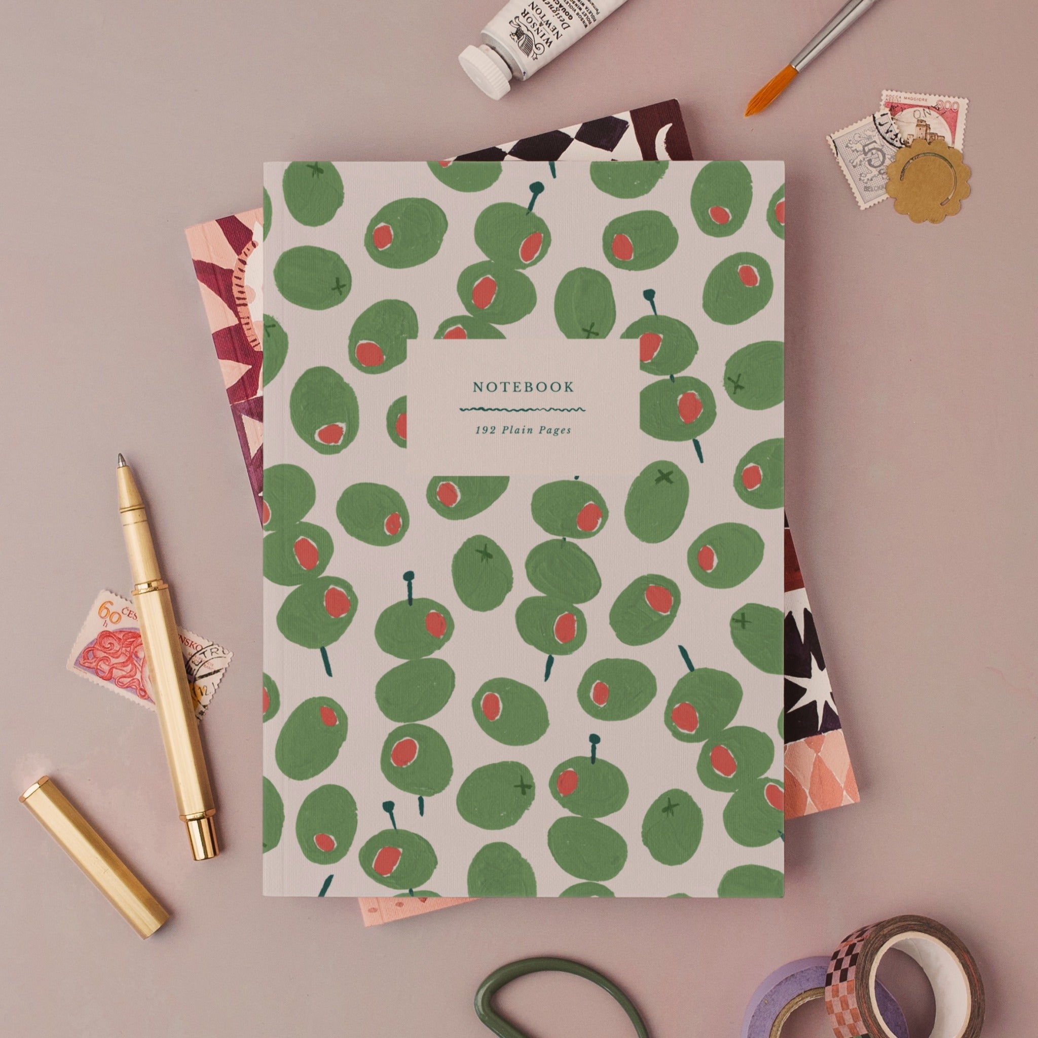 Olives notebook, A5 plain page journal styled in a flat lay with a gold pen, paints and vintage stamps