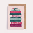 Christmas card with bookish theme, featuring an illustrated stack of book with decorative festive foliage and Christmas theme titles such as a Christmas Carol and The Nutcracker