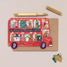 A Christmas card cut into the shape of bus full of reindeer from the wholesale Christmas card collection at Sister Paper Co.