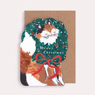 A Christmas card cut into the shape of a cat poking it's little face through a wreath from the wholesale Christmas card collection at Sister Paper Co.