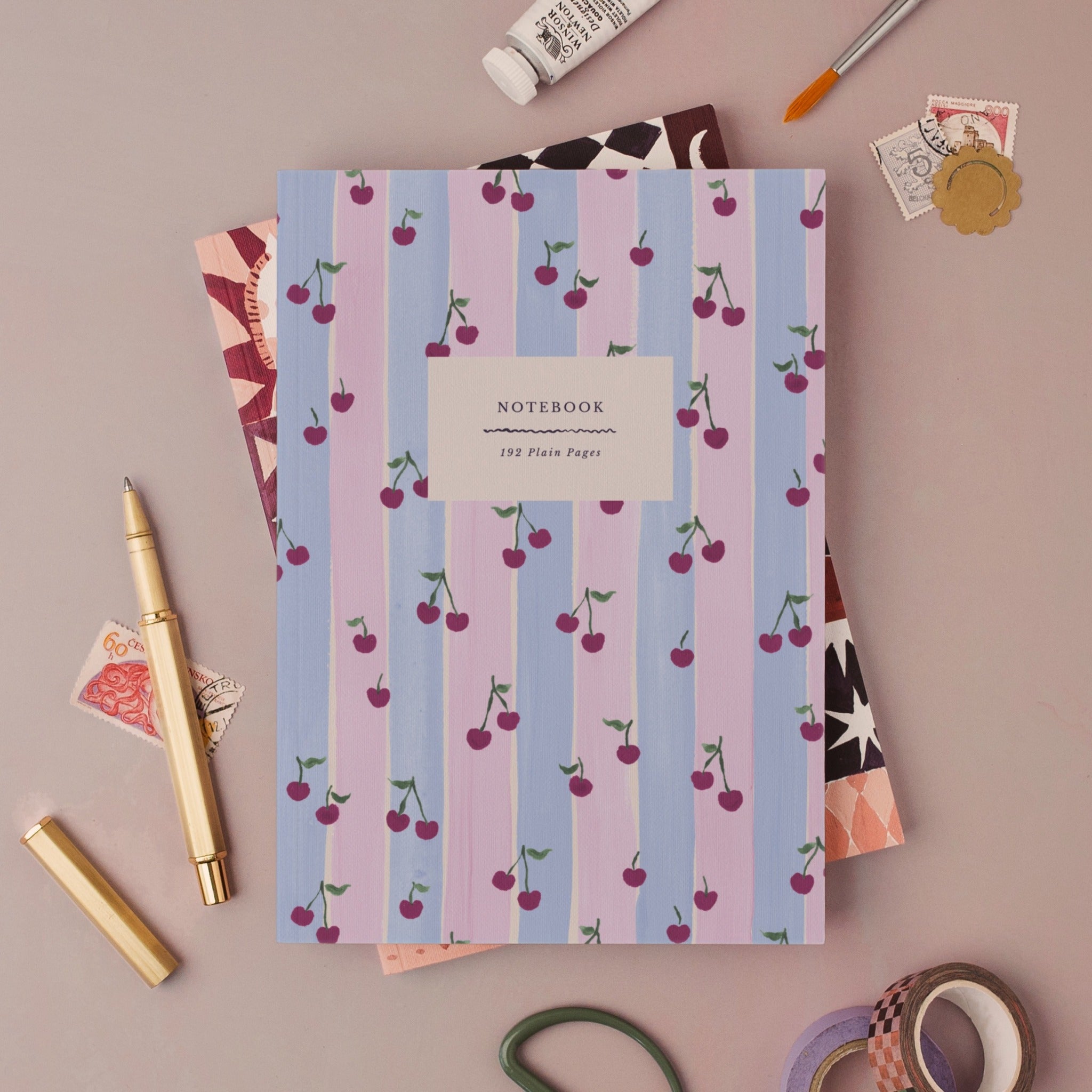 Cherries notebook, A5 plain page journal styled in a flat lay with a gold pen, paints and vintage stamps