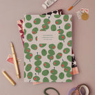 Olives notebook, A5 plain page journal styled in a flat lay with a gold pen, paints and vintage stamps
